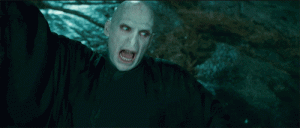 Actor Ralph Fiennes in character as Lord Voldemort from the Harry Potter film franchise with one arm raised and mouth agape